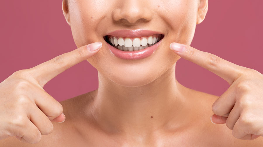 A woman proudly displays her teeth with her fingers, showcasing the results of her root canal therapy