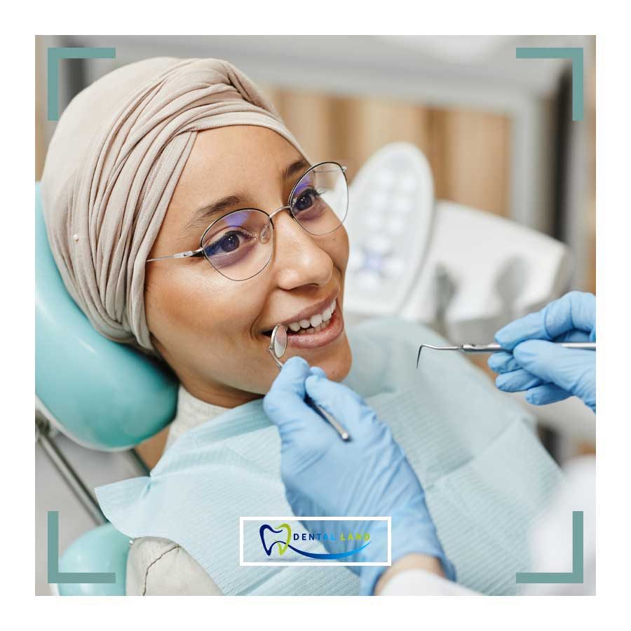 A woman wearing a head scarf is having her teeth examined during a dental check-up