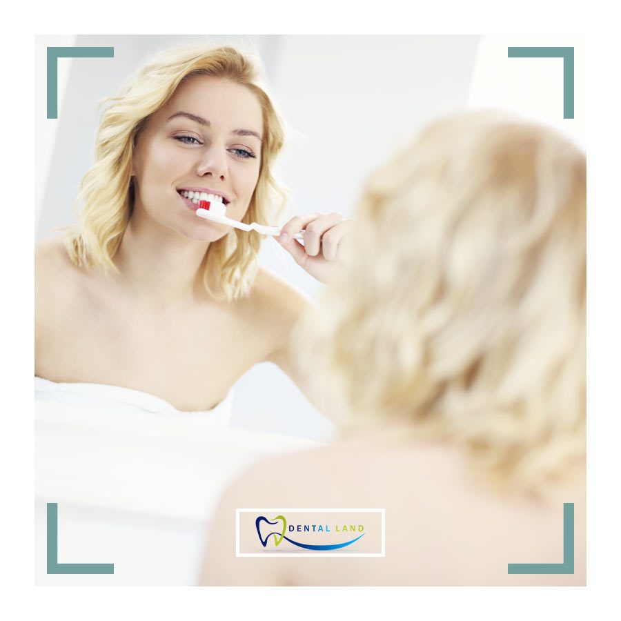 Woman brushing teeth in front of mirror