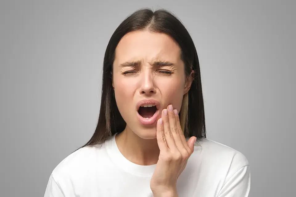 studio-shot-of-woman-feeling-pain-holding-cheek-s What's the Real Wisdom Teeth Removal Recovery Time?